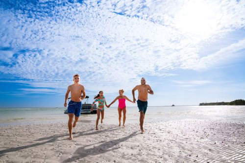 018-Image-2-New-Port-Richey-Windsong-Charters-and-Boat-Rentals-Family-running-onto-beach-at-Anclote-Key-2024-Roundhouse-Creative